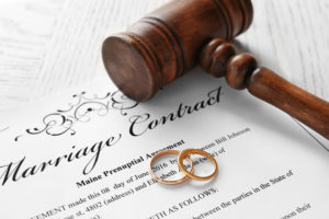 Keeping A Divorce Process Low-Stress -Golden wedding rings with judge gavel on marriage contract, closeup